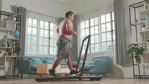 Asian Fat Man Wearing No T-Shirt And Running On A Treadmill At Home