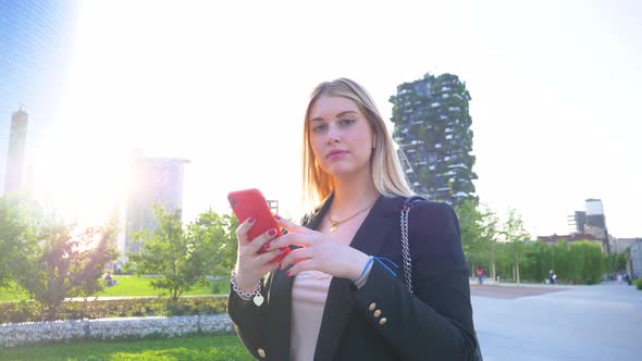 Slow motion shot of businesswoman using red smartphone in park