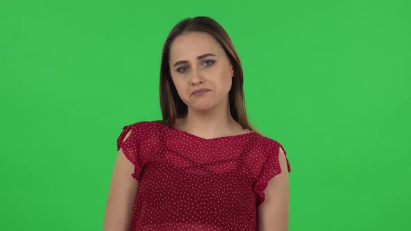 Portrait of Tender Girl in Red Dress Is Upset and Sighing. Green Screen