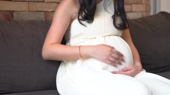Pregnant Woman Touching Baby Inside Stomach on Sofa