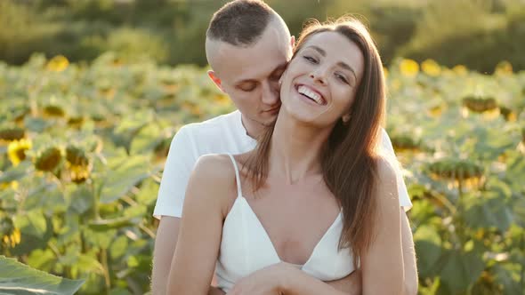 Happy Young Attractive Couple in Sunflower Field Together at Sunset in Slow Motion
