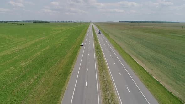 Trucks and Cars Ride Along the Highway Through the Field