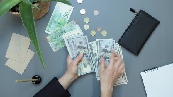 Female accountant counting money dollar bills at workplace.