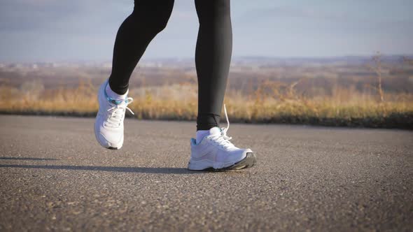 Close Up of Women's Legs Running on Asphalt Road