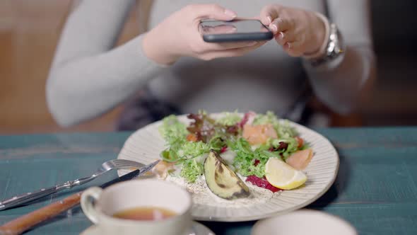 Unrecognizable Slim Woman Taking Photo of Healthful Dietary Salad with Vegetables and Fish in