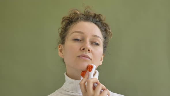 Young Woman with Curly Brown Hair Massages Cheek By Wall