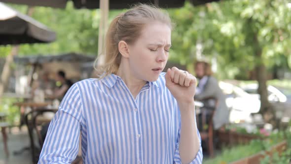 Sick Young Woman Coughing while Sitting in Cafe Terrace