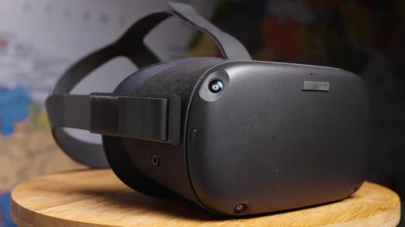 Black virtual reality glasses with four cameras on a wooden board against a world map