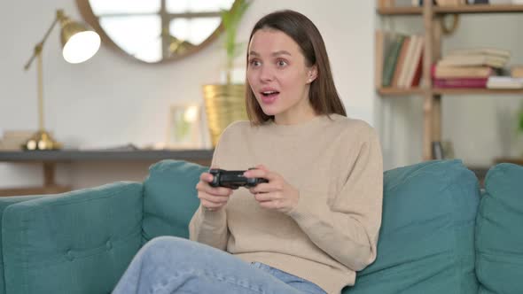 Young Woman Celebrating Success on Video Game on Sofa