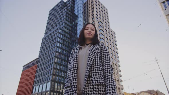 Lowangle Approaching Shot to a Young Adult Asian Woman in Downtown District Among Skyscrapers