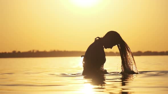 Silhouette of Woman Flipping Her Long Hair Back in Water. Slow Motion 240 Fps