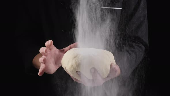 Flour is Poured Onto a Lump of Dough in the Hand of a Chef