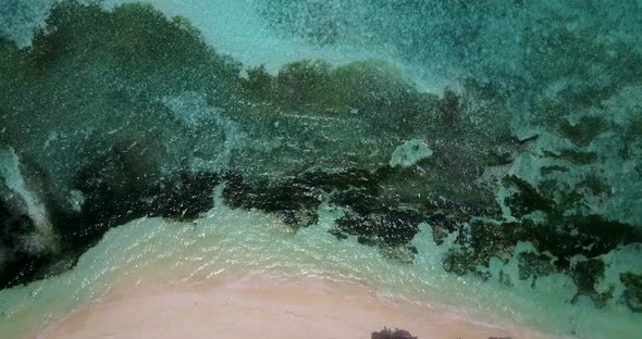 Daytime flying copy space shot of a white sandy paradise beach and blue water background in colorful