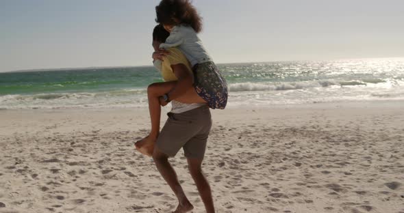 Man giving piggyback ride to woman on the beach 4k