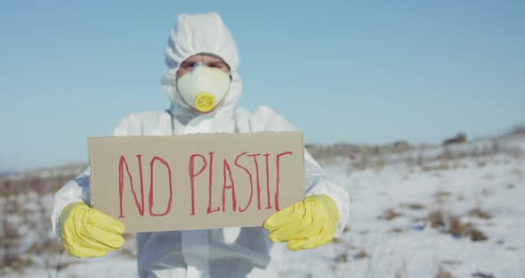 Man Wore in Protective Suit Holds No Plastic Sign on Abandoned Place in Winter