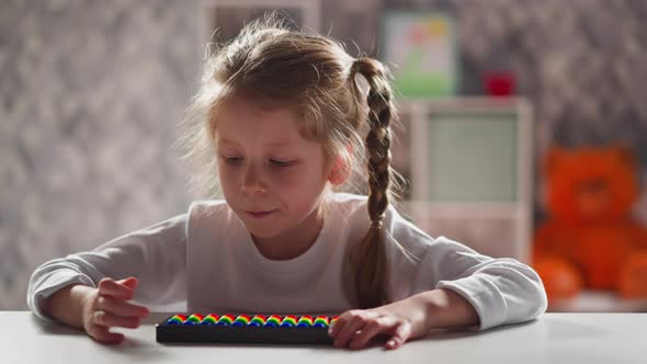 Little Child with Long Plaits Counts on Abacus at Lesson