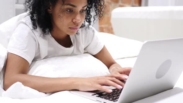 AfroAmerican Woman Working on Laptop Lying in Bed for Rest