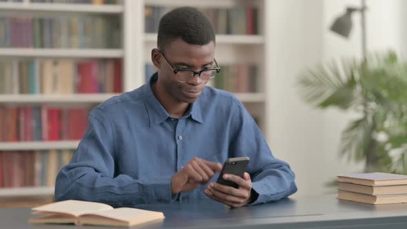 Young African Man Using Smartphone in Office