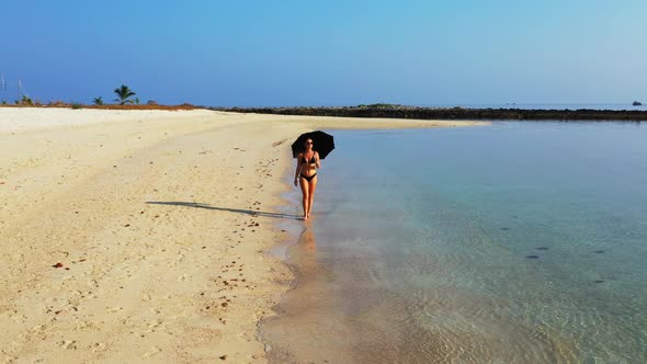 Female models sunbathing on idyllic sea view beach lifestyle by blue lagoon with white sandy backgro