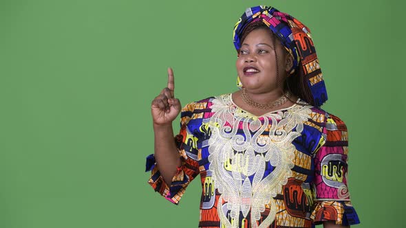 Overweight Beautiful African Woman Wearing Traditional Clothing Against Green Background