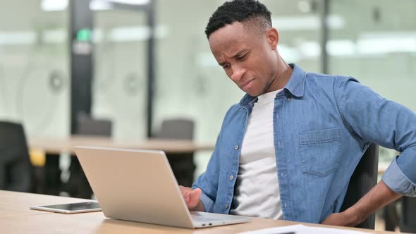 Casual African Man with Laptop Having Back Pain in Office 