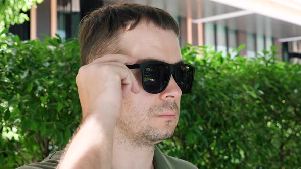 Man Looking From Under Black Sunglasses Showing Bloodshot Eye with Inflammation