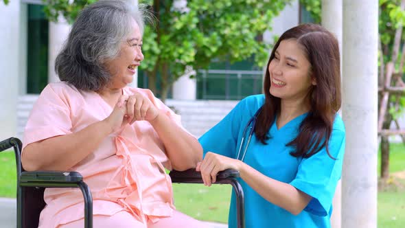 Asian careful caregiver or nurse taking care of the patient in a wheelchair.  Concept of happy retir
