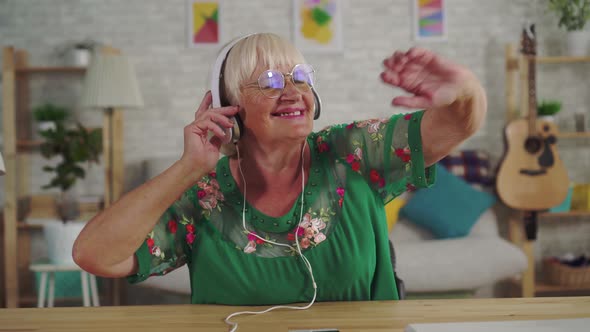 Cheerful Old Woman with Gray Hair in Headphones Listening To Music and Dancing Close Up