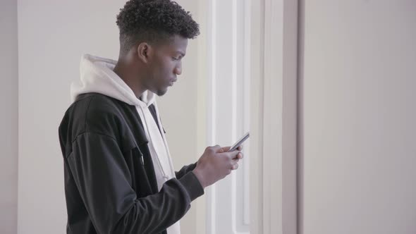 Profile of Serious Young Man Using Mobile Phone Indoors