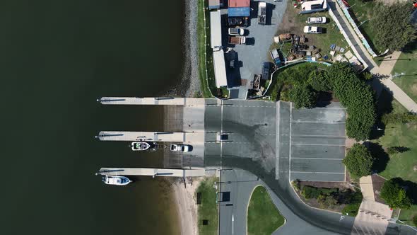 A car and trailer driving away from a boat ramp after launching a vessel in the water. High drone vi