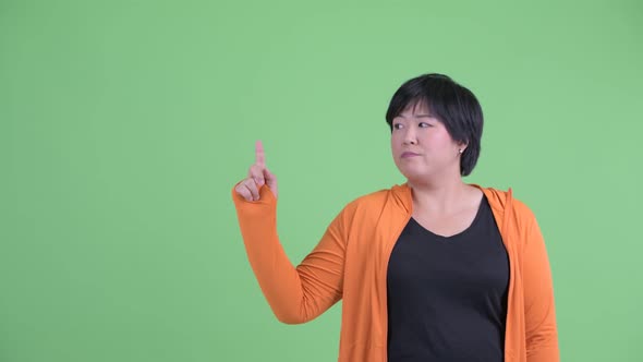 Stressed Young Overweight Asian Woman Pointing Up Ready for Gym