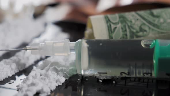 Money and drugs on a black glass table. Money, syringe and drugs.