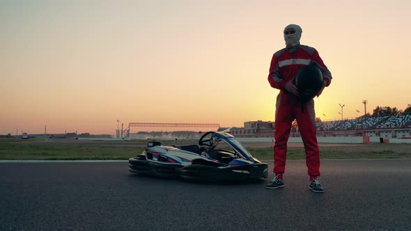 A Racer is Standing Next to a Car and Puts a Helmet on