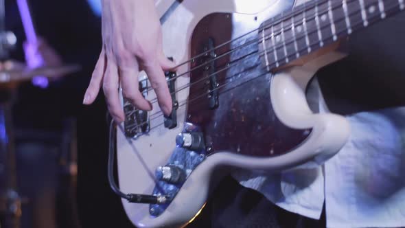 Young man playing electric bass guitar on the stage slow motion