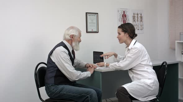 Senior Man Discussing Results With Doctor On Digital Tablet Good News