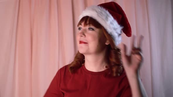 Woman wearing santa hat is smiling and dancing cheerfully