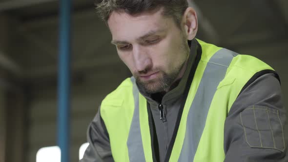 Close-up Face of Concentrated Brown-eyed Caucasian Man in Green Vest Looking Down. Professional