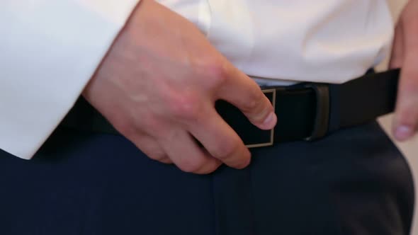 Man Fastens the Belt on His Trousers Closeup