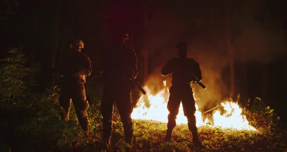Backlit Silhouette of Special Forces Marine Operators in Forest on Fire Explosion Background