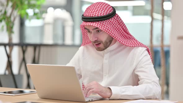 Cheerful Arab Businessman Celebrating Success on Laptop in Office 