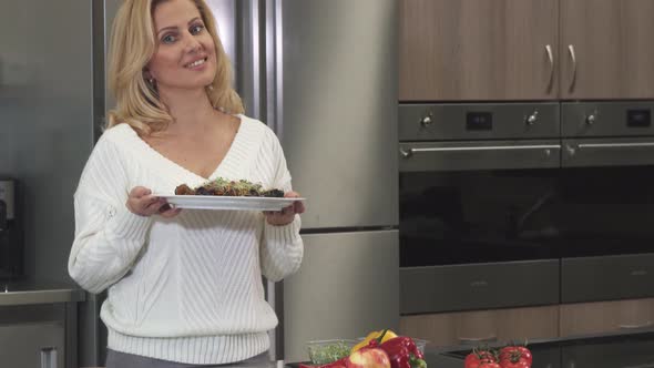 Beautiful Mature Woman Smiling To the Camera Posing with a Dish After Cooking