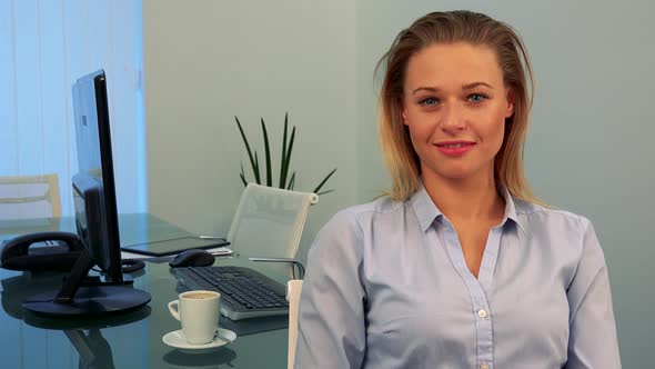 A Young, Beautiful Woman Smiles and Shows a Thumb Up To the Camera in an Office