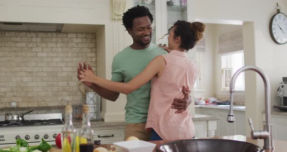 Happy biracial couple dancing together in kitchen