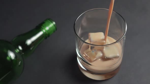 Irish cream liqueur is poured into a glass with ice cubes