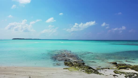 Wide angle flying tourism shot of a summer white paradise sand beach and blue sea background in colo