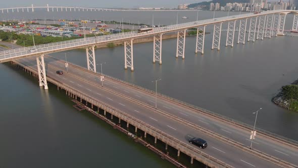 Drone tilt reveal shot of Praia Grande bridge passing over road beside Nam Van Lake, with Taipa and