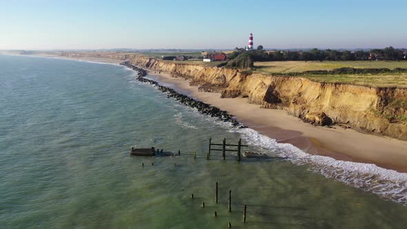 Steady footage by drone of the sea defences at Happiburgh, Norfolk Uk with the lighthouse in the bac