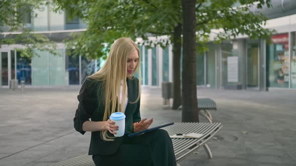 Young Business Woman Using Tablet and Drinking Coffee. Modern Executive Girl in Suit Sitting on