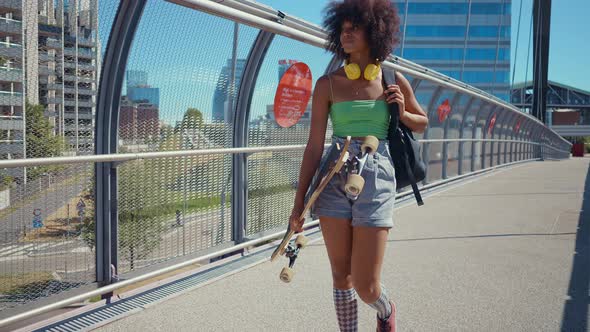 Beautiful young woman cruising around the city with her longboard.