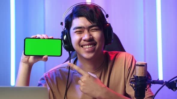Asian Man Holding Mobile Phone With Mock Up Green Screen While Live Stream